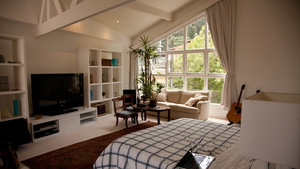 A well-lit living room with a large window, a television, a laptop on the bed, and a guitar. - São Conrado Classy (Rio de Janeiro)