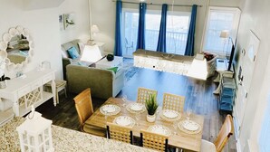A dining area with a wooden table set for four, surrounded by chairs. There is a ceiling fan above the table, and a window with curtains in the background. - SunburstParadise: LUX TH OceanView DOWNTOWN BOARDWALK 3BR 3BA with 2 Car Garage (Ocean City)