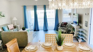 A dining area with a wooden table set for four, a potted plant, and a chandelier. - SunburstParadise: LUX TH OceanView DOWNTOWN BOARDWALK 3BR 3BA with 2 Car Garage (Ocean City)