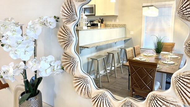 A dining area with a mirror, white orchids, and a kitchen in the background. - SunburstParadise: LUX TH OceanView DOWNTOWN BOARDWALK 3BR 3BA with 2 Car Garage (Ocean City)