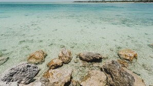 Mare turchese trasparente con rocce ben visibili a riva.