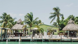 Un resort con capanne a tetto di paglia, una piscina e palme.