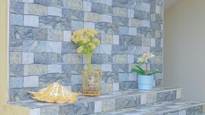 Un mur de pierre orné d’un vase de fleurs et d’un objet décoratif posé sur une étagère.