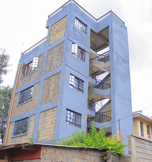 A multi-story building with a blue facade, multiple balconies, and visible windows.