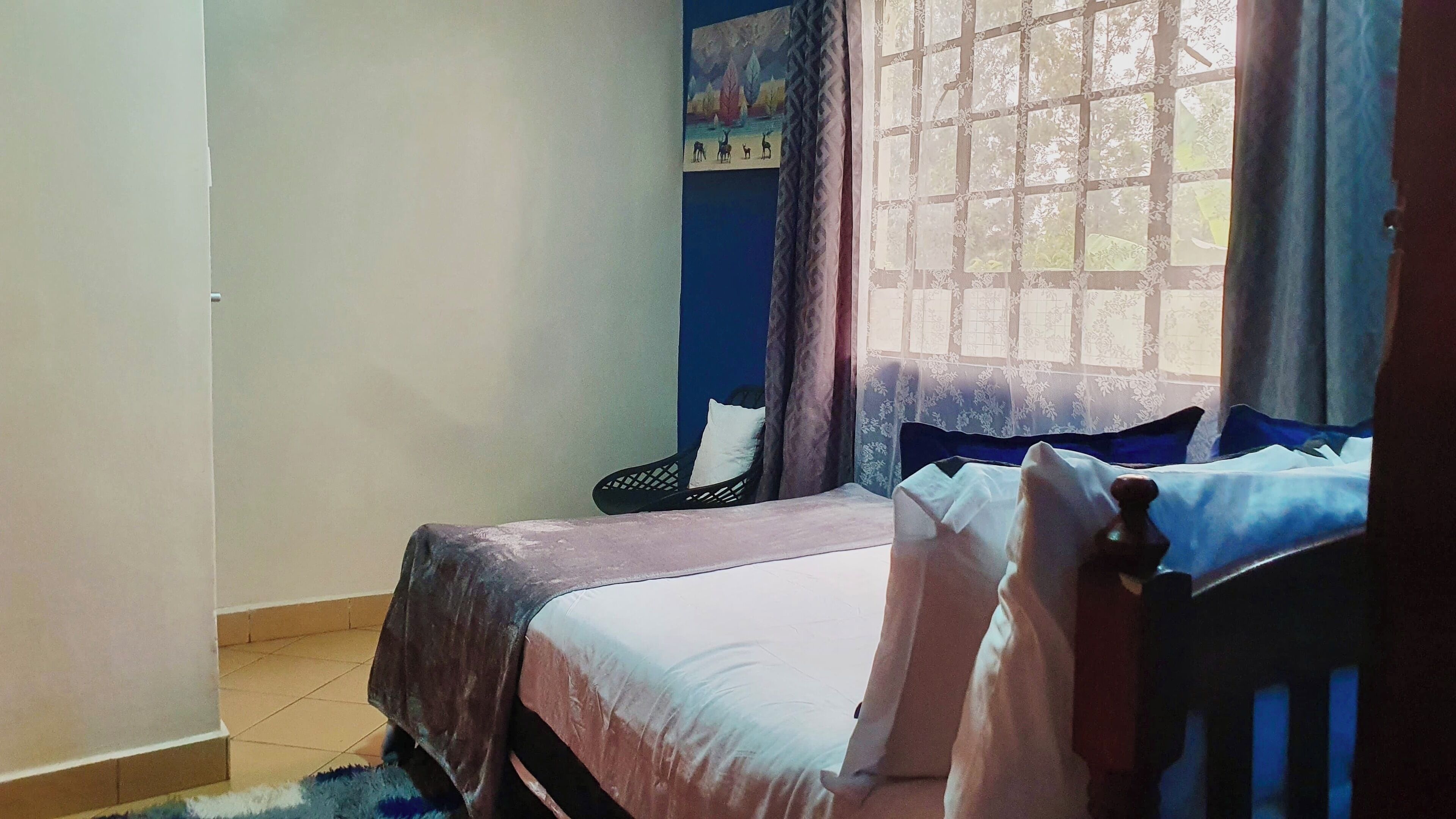 A bedroom with a bed, a chair, and a window with curtains.