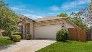 A two-story house with a garage, a front yard with a lawn, and a wooden fence.