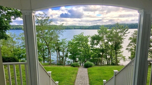 A covered porch with a view of a lake and trees. - Lake Front Property on the main channel of Barkley Lake-Private Paradise (Eddyville)