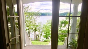 A wooden door with a glass panel leading to a deck with a view of a lake and trees. - Lake Front Property on the main channel of Barkley Lake-Private Paradise (Eddyville)
