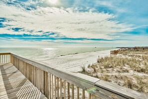 A wooden deck overlooking a beach with a wooden pier in the distance. - Sunset Jetty View! Enjoy one free beach chair set up and umbrella each day of yo (Destin)