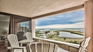 A balcony with Adirondack chairs and a view of a river and buildings. - Sunset Jetty View! Enjoy one free beach chair set up and umbrella each day of yo (Destin)