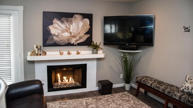 Ein Wohnzimmer mit Kamin, einem Wandfernseher und einem großen Blumenbild.