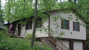 A white building with brown shutters, a wooden staircase, and an American flag.