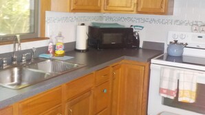 A kitchen with wooden cabinets, a stainless steel sink, a microwave, and a stove.