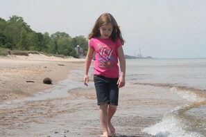 Een strandscène met een kind dat in ondiep water loopt.