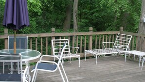 A wooden deck with outdoor furniture including a table, chairs, and a bench.