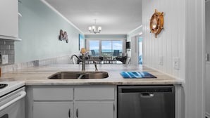 A modern kitchen with a large island, stainless steel appliances, and a view to the outside. - Direct OCEAN FRONT CONDO gorgeous view A Place at the Beach, Beautifully Updated (Atlantic Beach)