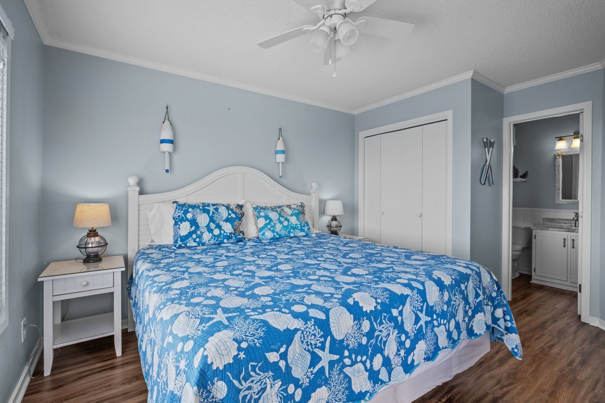A bedroom with a bed, nightstands, a ceiling fan, and a bathroom visible through an open door.