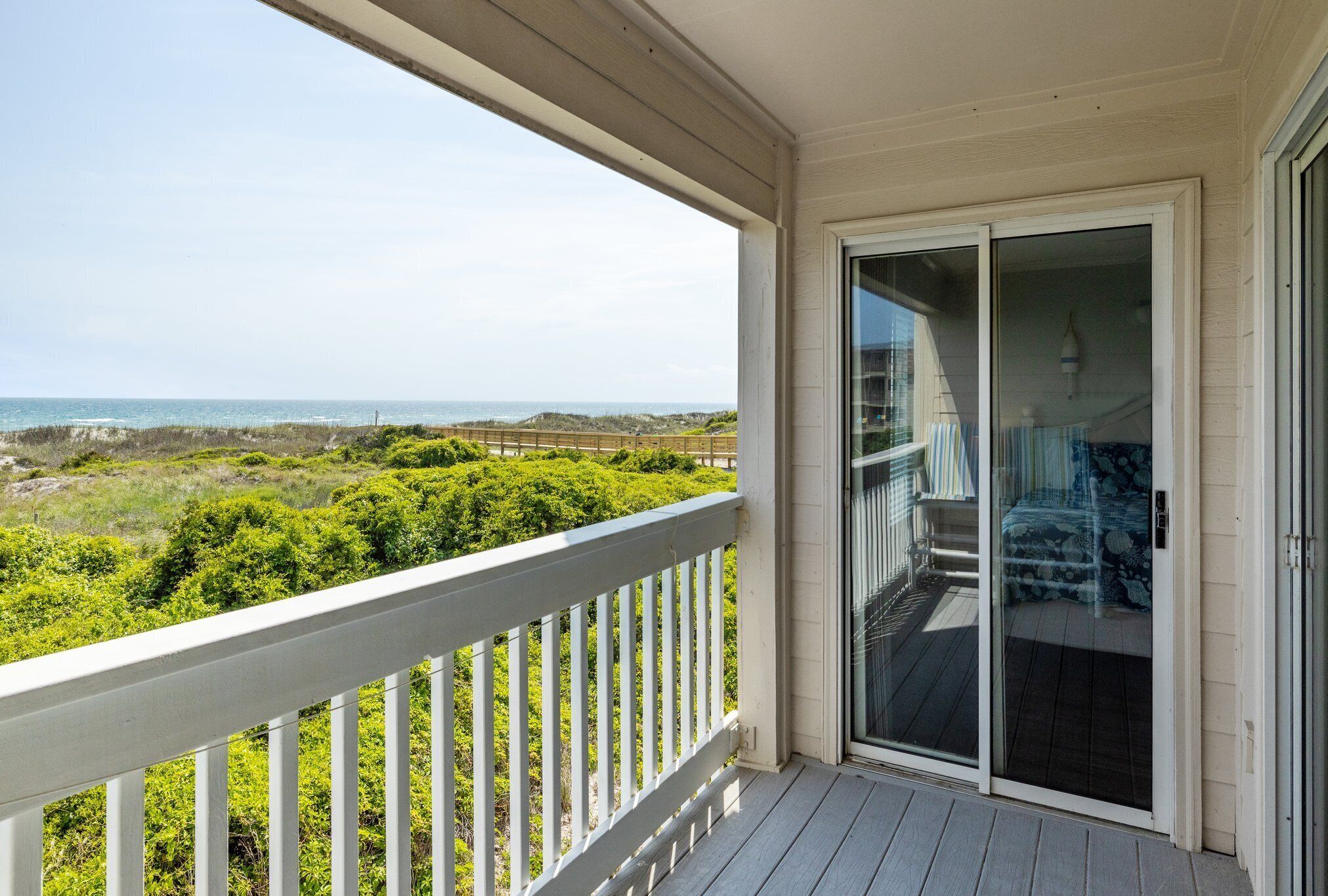 A balcony with a view of the ocean and beach vegetation.