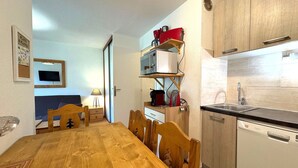 A compact kitchen with a wooden table and chairs, a microwave, a coffee maker, and a dishwasher.