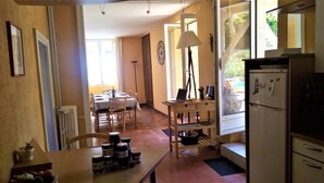 Eine Küche mit Kühlschrank, einem Esstisch mit Stühlen und einem Fenster mit Vorhängen.