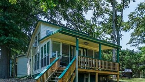 A two-story house with a covered porch and a staircase leading to the upper level.