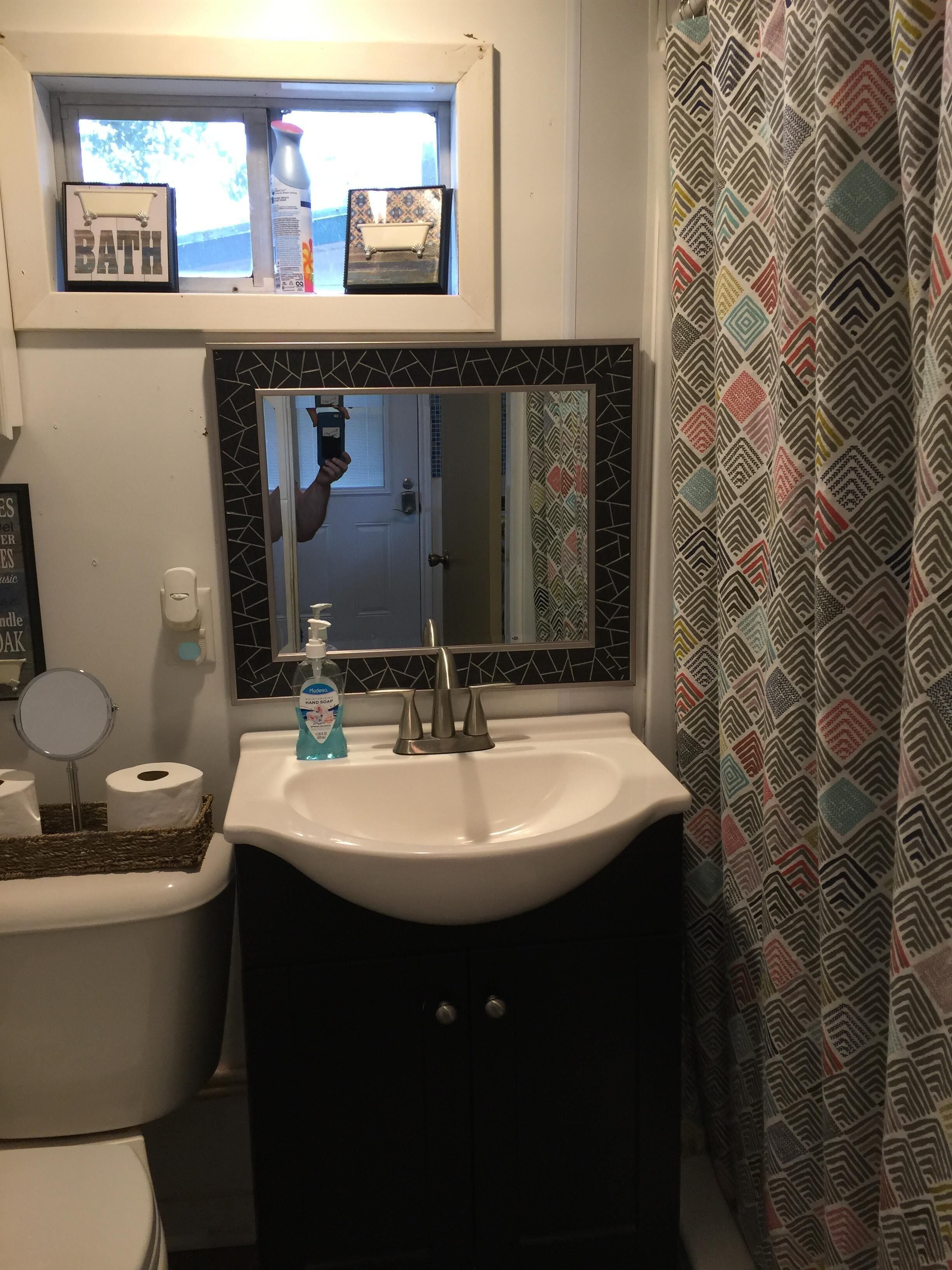 A bathroom with a white sink, a mirror, a toilet, and a shower curtain.
