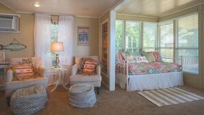 A cozy room with a bed, two chairs, a table, and a window.