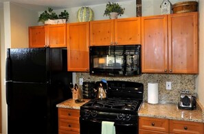 Kitchen equipped with a refrigerator, stove, microwave, sink, and various kitchen essentials.