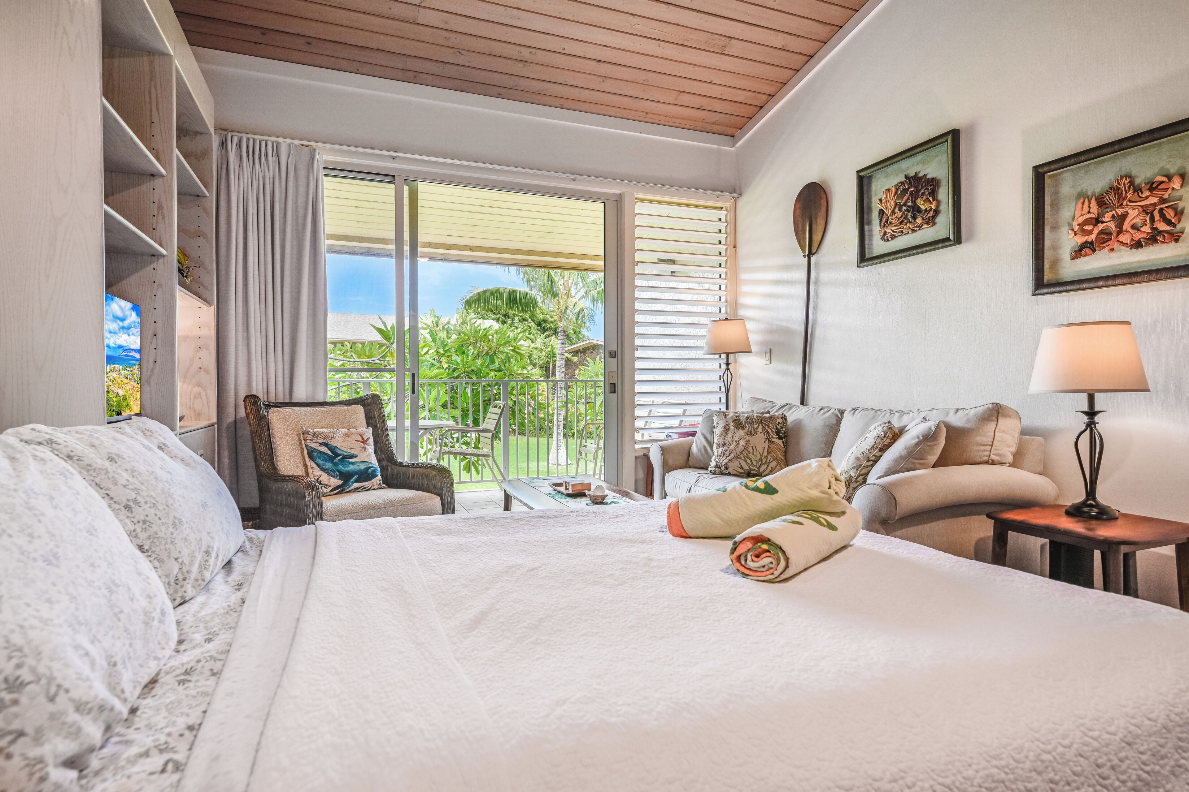 A hotel room with a bed, two sofas, a chair, a table, and a balcony with a view.