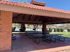 A covered picnic area with benches and a brick wall.