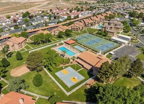 Vue aérienne d’un quartier résidentiel avec des maisons, un court de tennis et une piscine.