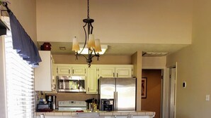 Una cocina amplia con una isla central, armarios blancos y una lámpara de araña.
