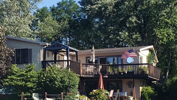 A waterfront property with a dock, outdoor seating, and a flag. - Beautiful Waterfront Home on Baugo Bay (Osceola)