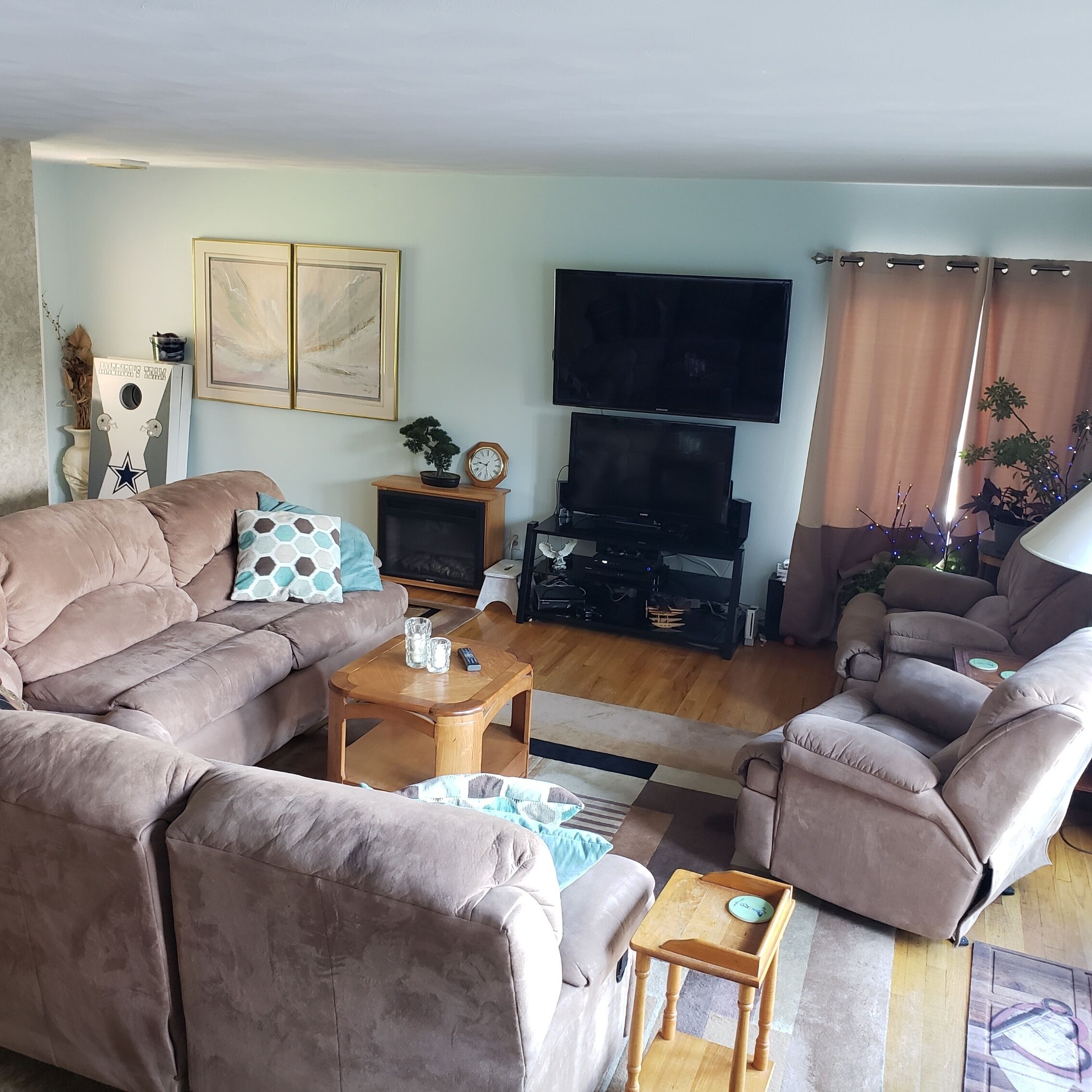 Een woonkamer met een beige bank, een houten salontafel, een televisie en een bijzettafeltje.
