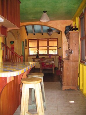 A kitchen with a bar area, wooden stools, and a dining table. - Beach House with Paddle Boards & Water Toys (Maya Beach)