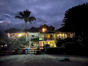A beachfront property with multiple buildings, a pool area, and a palm tree.
