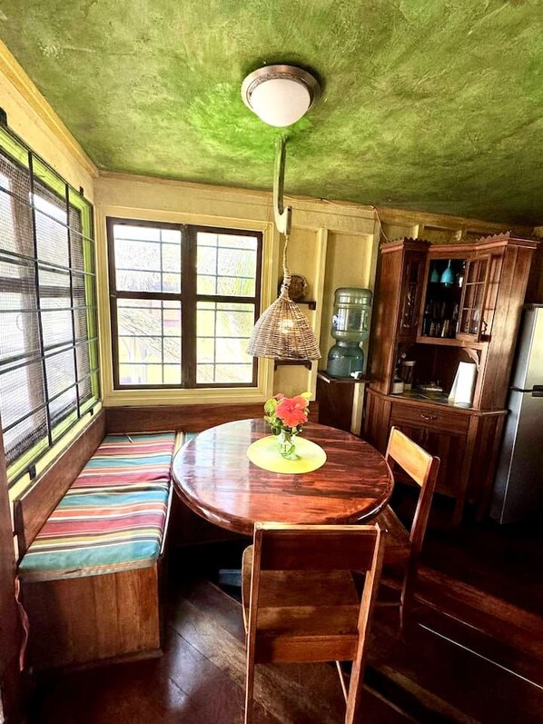 A dining area with a round wooden table, bench seating, and a hanging lamp.