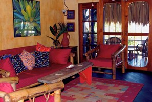Ein gemütliches Zimmer mit einer Holzsofa, einem roten Sessel, einem Holztisch und einem großen Fenster mit Blick.