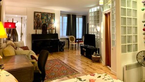 Un soggiorno con un pianoforte, un divano, un tavolino da caffè e un tappeto decorato.