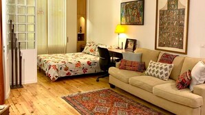 Un accogliente soggiorno con un letto, una poltrona, una scrivania e un grande tappeto.
