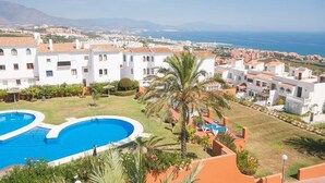A resort with a swimming pool, palm trees, and a view of the sea. - PENTHOUSE WITH AC, SEA VIEW, PANORAMIC TERRACE OF 100 M2 LOUNGE TRANSATS (ALCORRIN - PUERTO LA DUQUESA - COSTA DEL SOL)