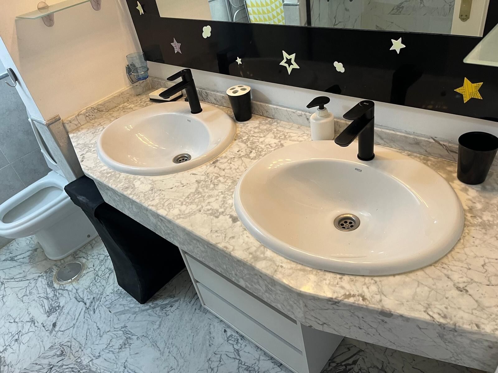 Une salle de bain avec deux lavabos, un miroir et des toilettes.