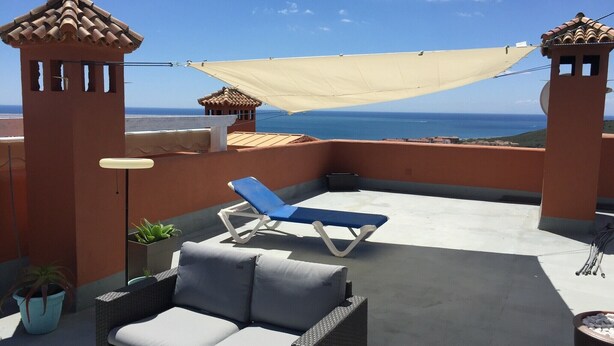A rooftop terrace with a blue lounge chair, a wicker sofa, and a view of the sea. - PENTHOUSE WITH AC, SEA VIEW, PANORAMIC TERRACE OF 100 M2 LOUNGE TRANSATS (ALCORRIN - PUERTO LA DUQUESA - COSTA DEL SOL)