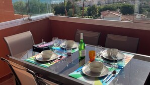 A dining area with a table set for four, overlooking a coastal view. - PENTHOUSE WITH AC, SEA VIEW, PANORAMIC TERRACE OF 100 M2 LOUNGE TRANSATS (ALCORRIN - PUERTO LA DUQUESA - COSTA DEL SOL)
