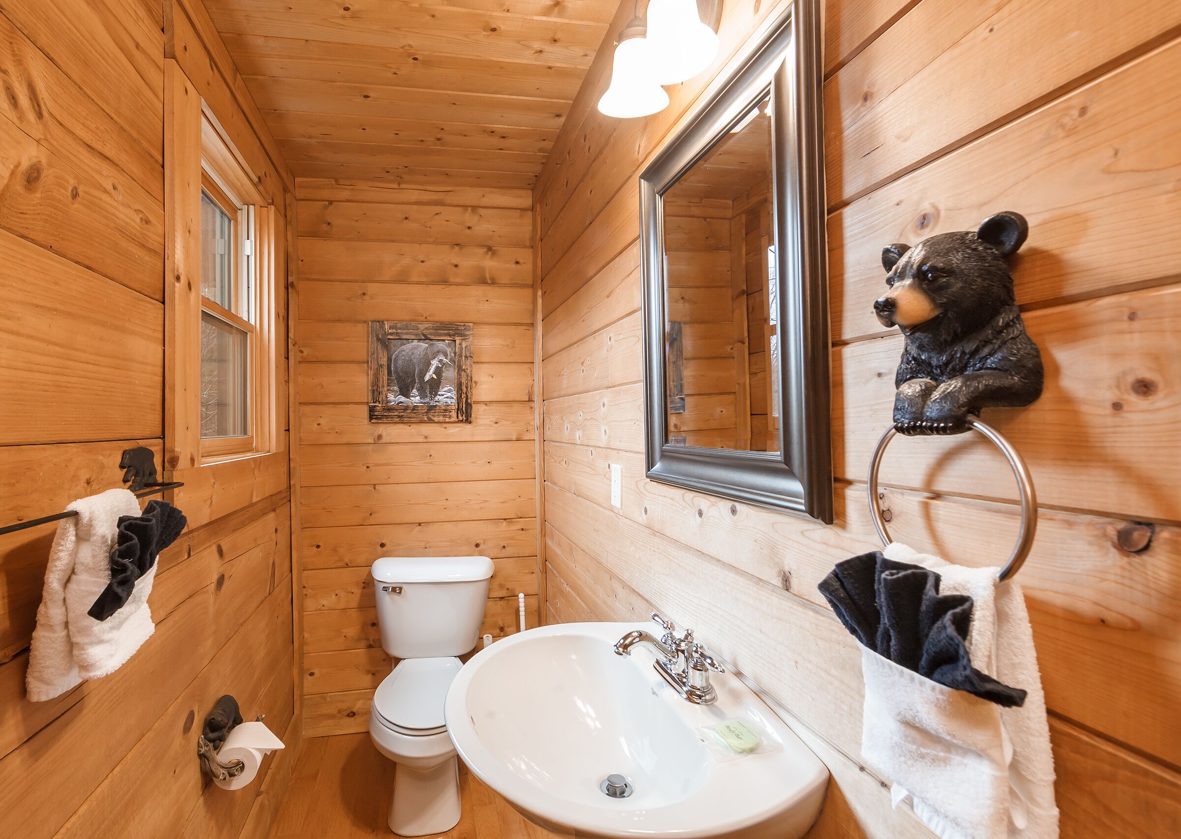 A wooden cabin bathroom with a toilet, sink, and mirror.