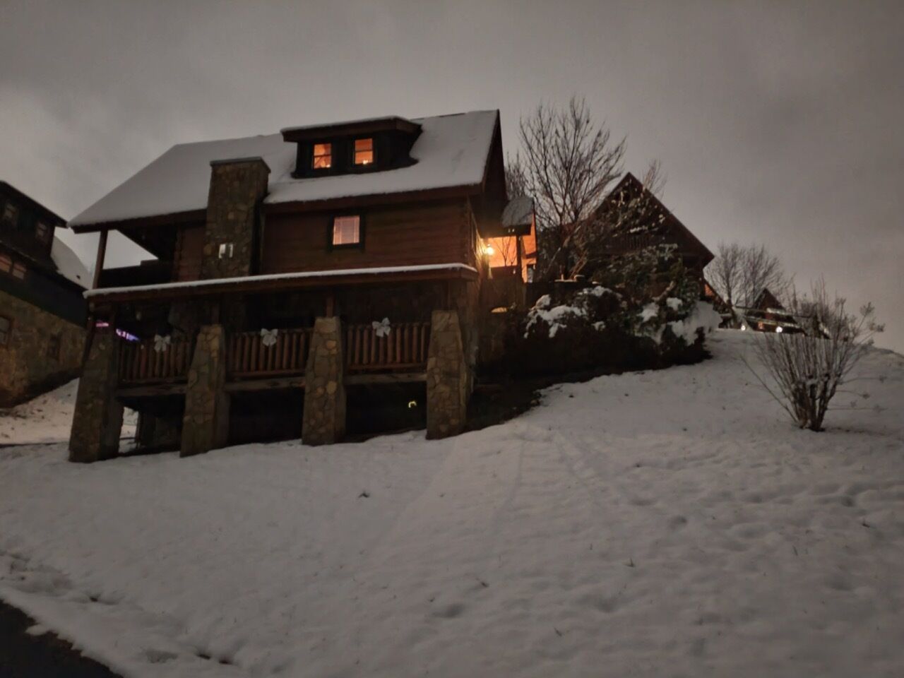 Eine Holzhütte mit Steinuntergrund, einer Veranda und verschneiter Landschaft.