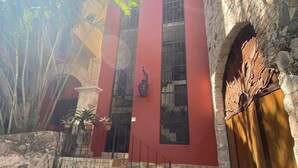 A red building with stone walls, a wooden door, and a staircase leading to the entrance.