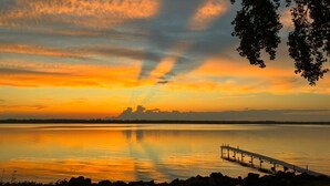 A sunset over a calm body of water with a pier extending into the water.