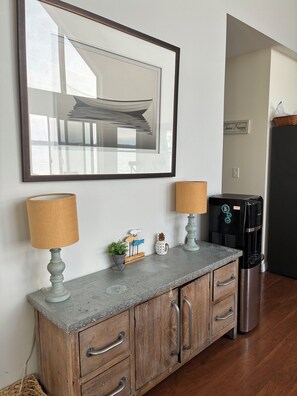 A kitchenette with a coffee maker, a framed picture, and a welcome sign.