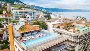A hotel with a rooftop pool, multiple balconies, and a view of the sea. - Designer 2BR w/ Balcony & Pool in Romantic Zone (Puerto Vallarta)